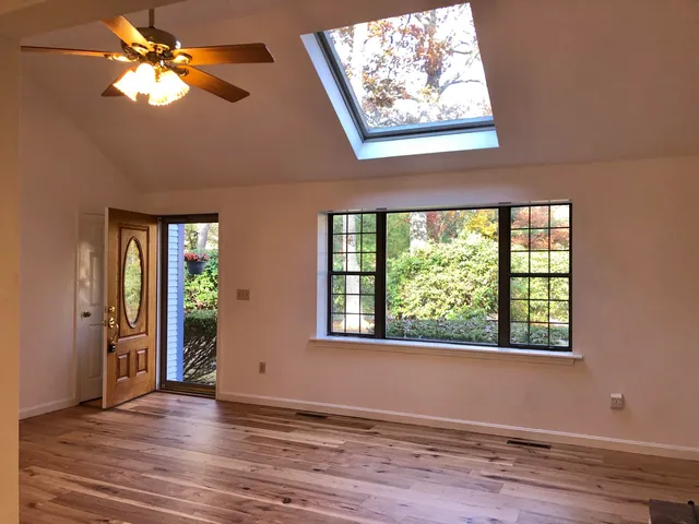a view of an empty room with window and wooden floor