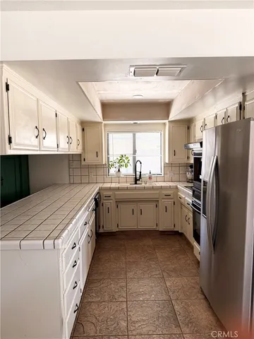 a kitchen with stainless steel appliances a refrigerator sink and white cabinets