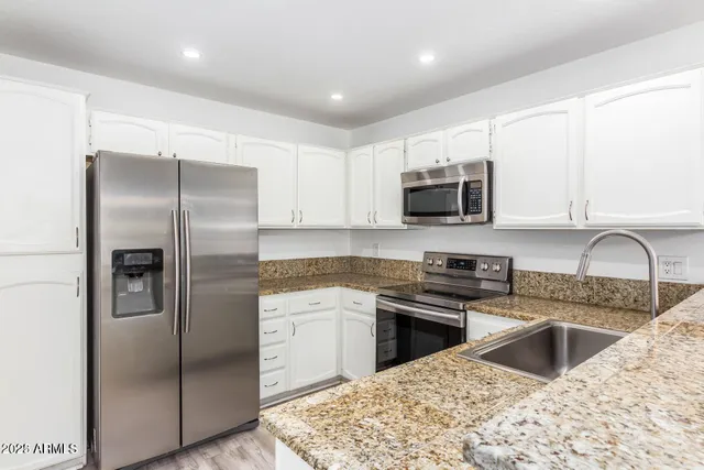 a kitchen with granite countertop a refrigerator sink and microwave