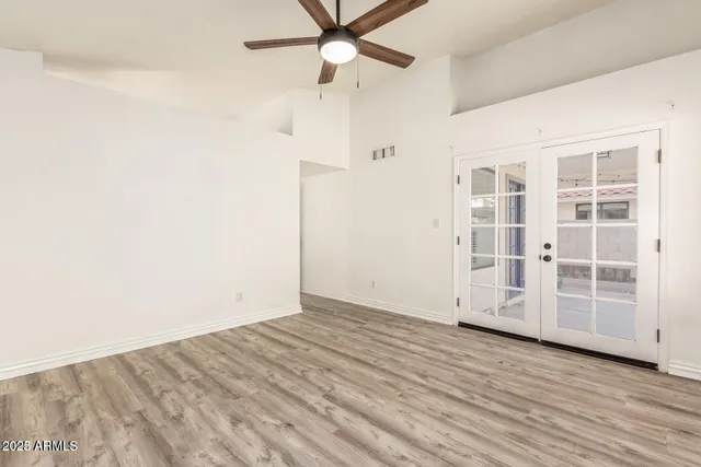 an empty room with wooden floor closet and windows