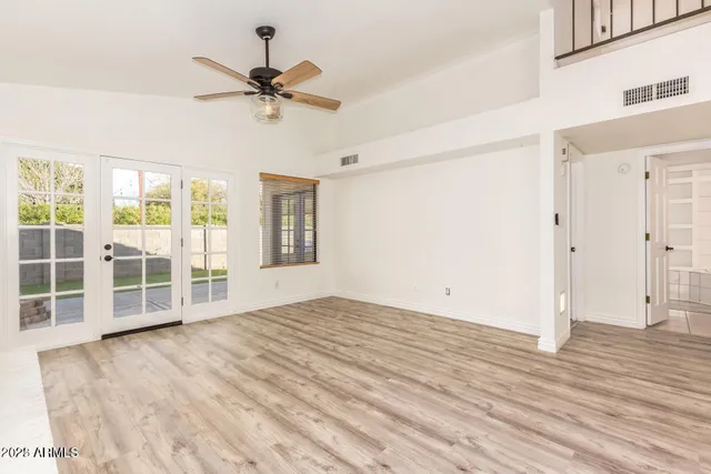 an empty room with wooden floor fan and windows