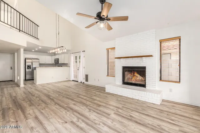 a view of a livingroom with a fireplace a ceiling fan and wooden floor