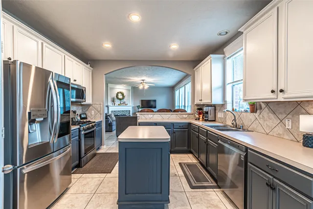 a kitchen with stainless steel appliances granite countertop a refrigerator a sink dishwasher a stove and white countertops with wooden floor