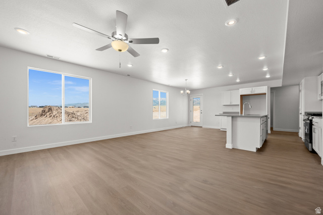 1554 Pheasant Road Eagle Mountain, UT 84005 - Photo 5 of 29 Unfurnished living room featuring a ceiling fan, dark wood-style flooring, and a chandelier