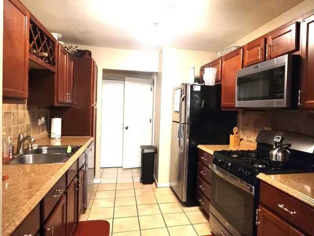 a kitchen with stainless steel appliances granite countertop a refrigerator a stove top oven and sink