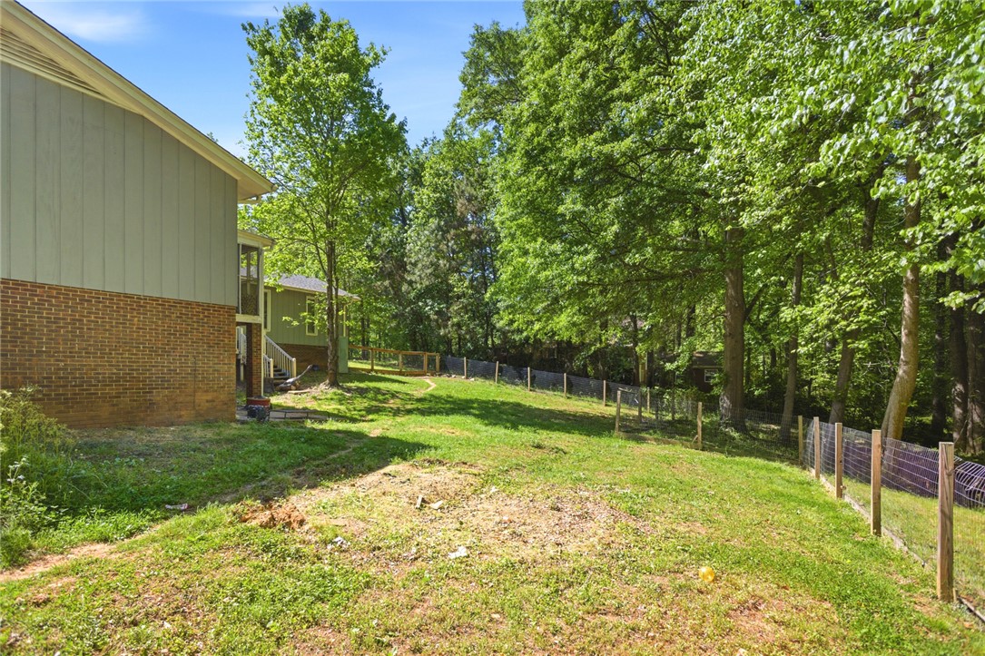 311 Cumberland Way Anderson, SC 29621 - Photo 40 of 44 A verdant backyard offers ample green space, bordered by mature trees and a sturdy fence.