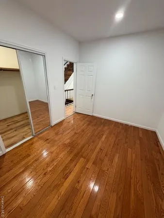 a view of an empty room with wooden floor and stairs