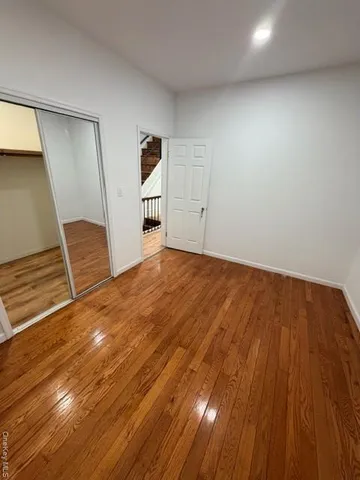 a view of an empty room with wooden floor and stairs
