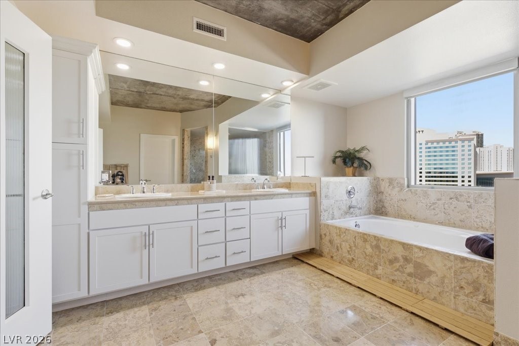 360 East Desert Inn Road, Unit 604 Las Vegas, NV 89109 - Photo 7 of 28 City views from a luxurious primary bathroom, featuring a deep soaking tub and a spacious double vanity.