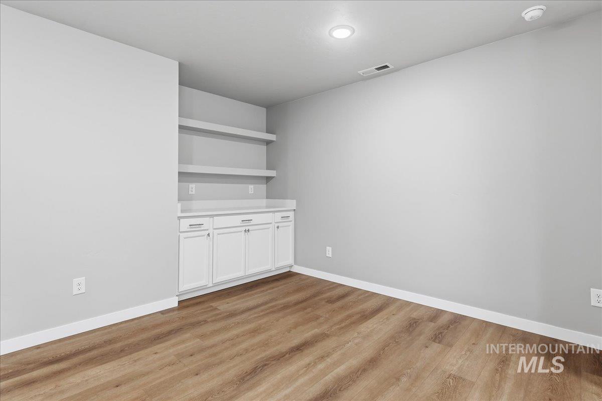 12475 West Victory Road Boise, ID 83709 - Photo 10 of 26 Room featuring wood-finish flooring, recessed lighting, and a built-in white cabinetry unit with a light-toned countertop and open shelving