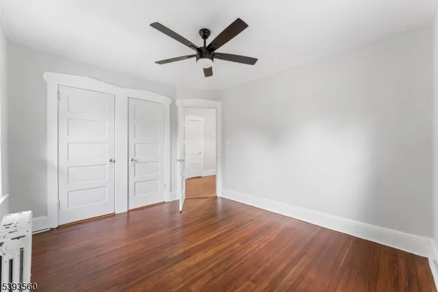 an empty room with wooden floor and a ceiling fan