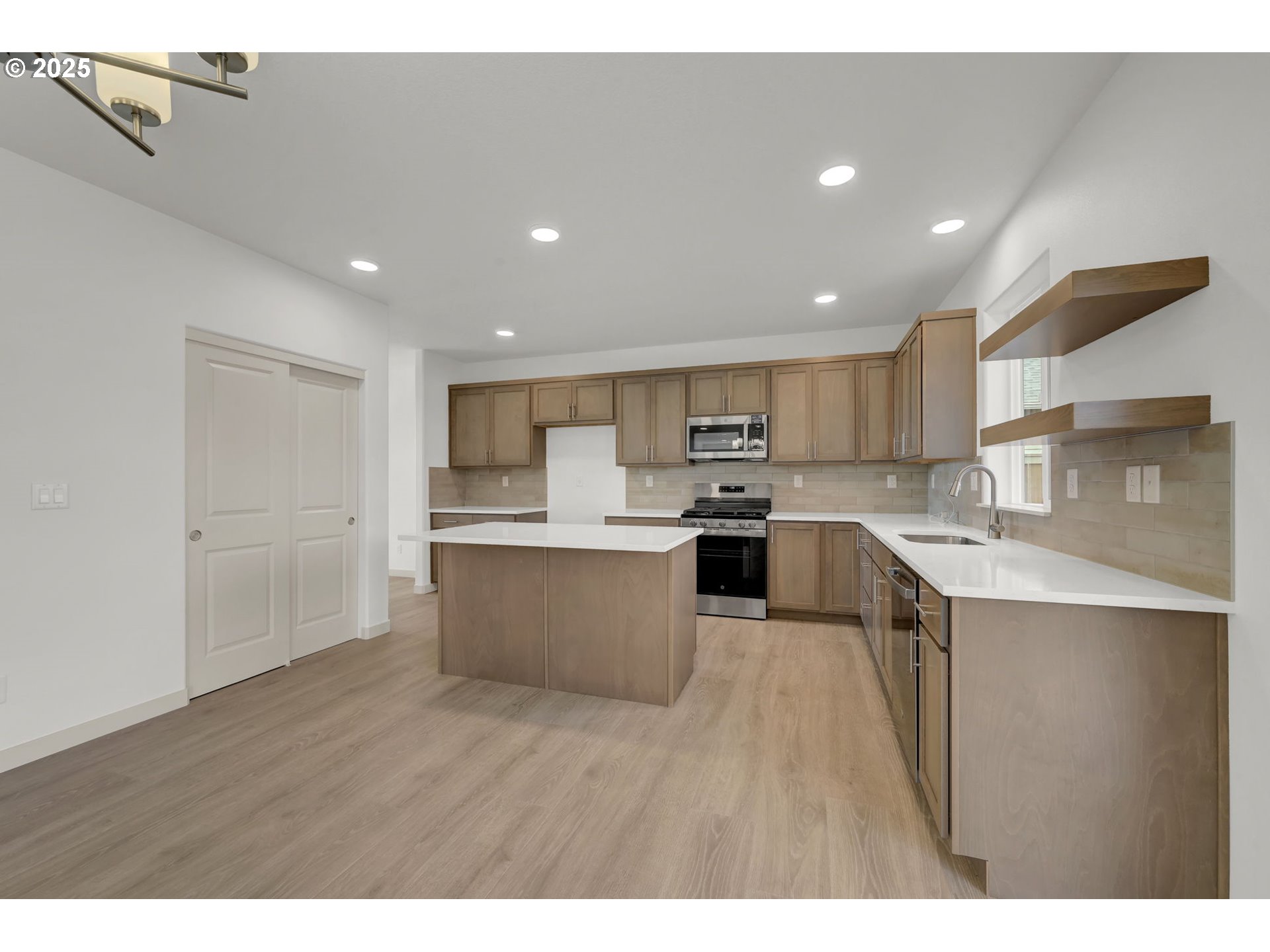 5653 Magnificence Way Eugene, OR 97402 - Photo 3 of 44 a large kitchen with kitchen island a sink a center island stainless steel appliances and a counter top space