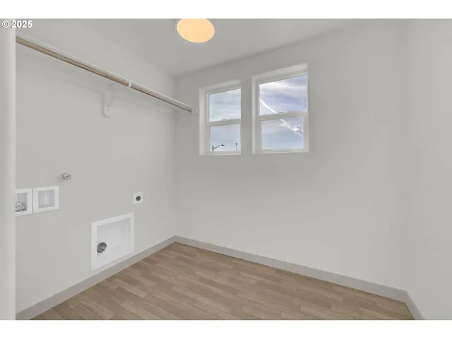 a view of an empty room with wooden floor and windows
