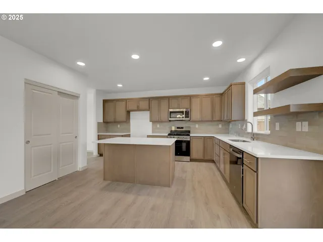 a kitchen with stainless steel appliances kitchen island sink refrigerator and cabinets