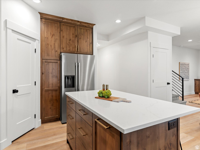 1267 West 2350 South Perry, UT 84302 - Photo 21 of 35 Kitchen island featuring a white countertop, wood-finish cabinetry, and gold-tone hardware