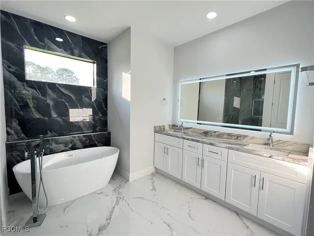 a bathroom with a sink a large mirror and a bathtub