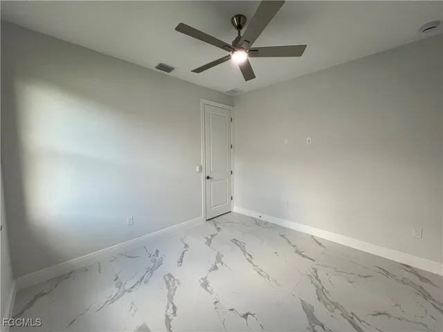 an empty room with a ceiling fan and a window