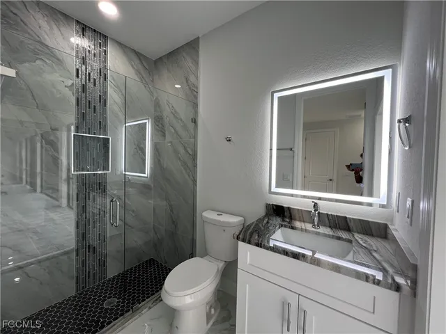a bathroom with a granite countertop sink toilet and shower
