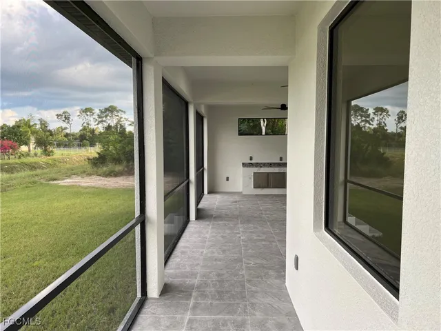 a view of an empty room with a window and kitchen view