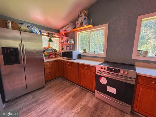 a kitchen with stainless steel appliances granite countertop a refrigerator a sink a stove and wooden floor