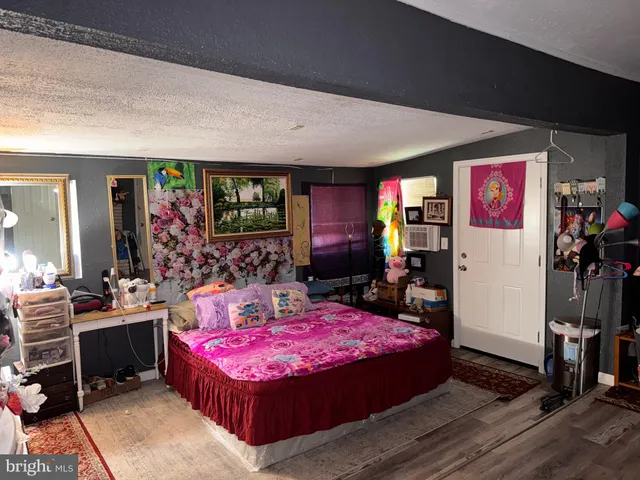 a bed room with a bed a dresser and paintings on the wall