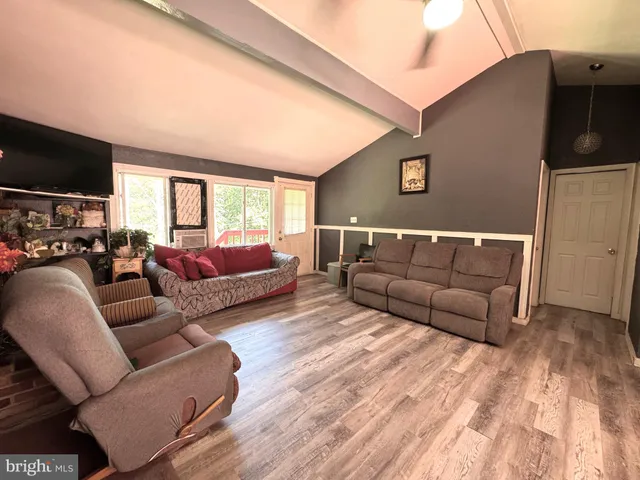 a living room with furniture a flat screen tv and a window