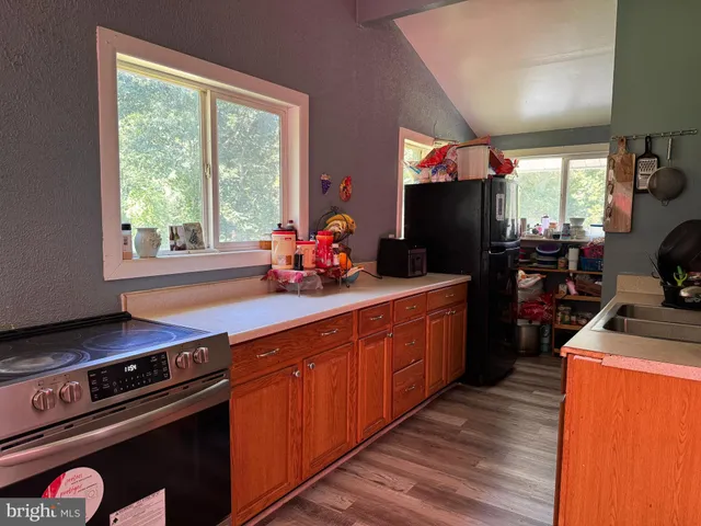 a kitchen with stainless steel appliances a sink dishwasher a stove a refrigerator and wooden floor