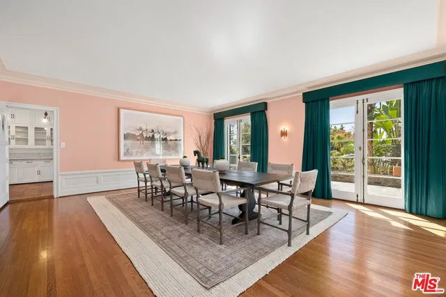 a dining room with wooden floor a glass table and a floor to ceiling window