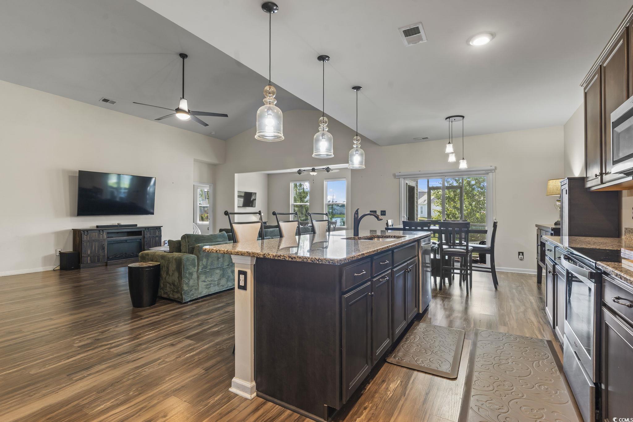 256 Copper Leaf Drive Myrtle Beach, SC 29588 - Photo 40 of 40 Kitchen with hanging light fixtures, light stone counters, open floor plan, dark wood-style flooring, and an island with sink
