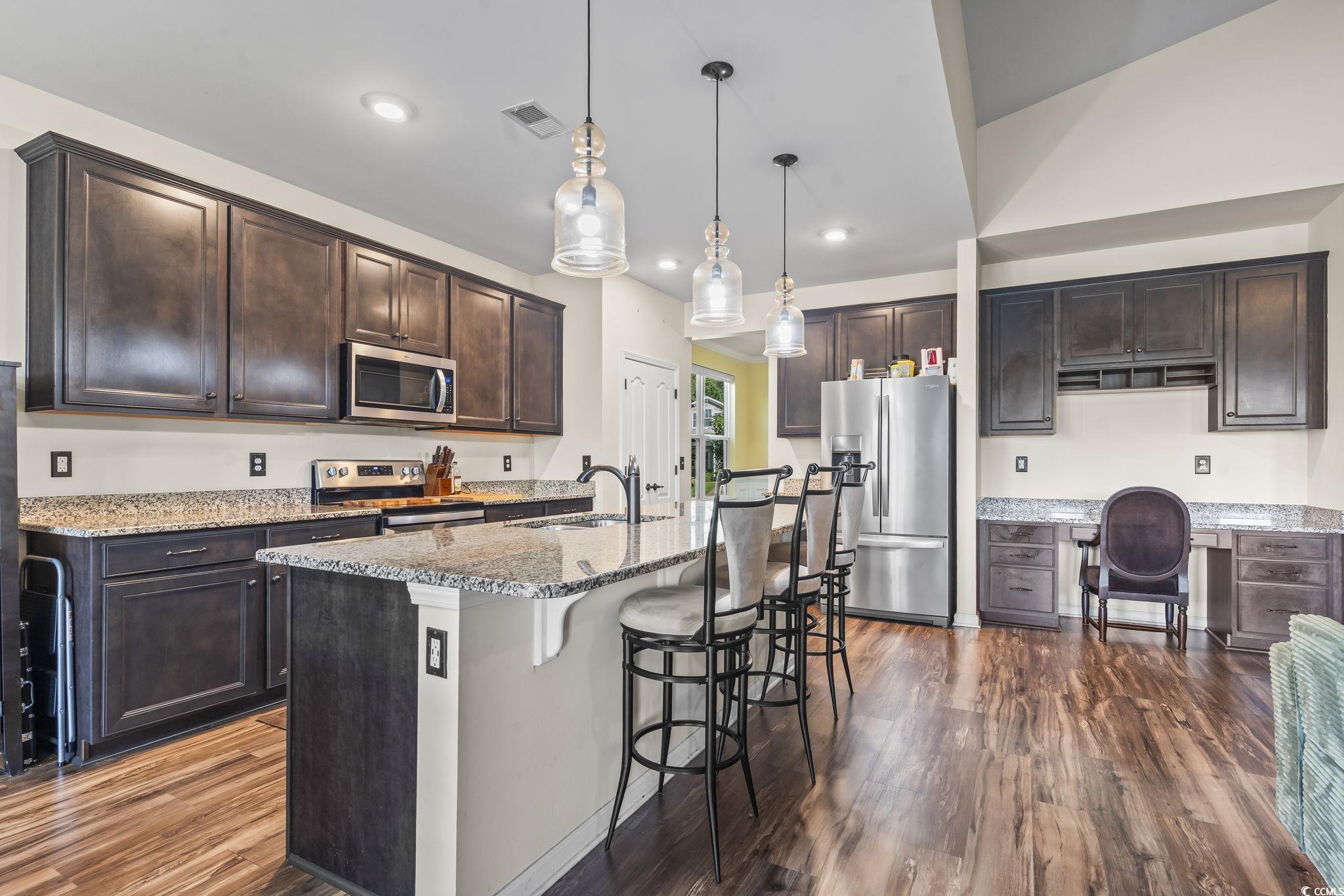 256 Copper Leaf Drive Myrtle Beach, SC 29588 - Photo 14 of 40 Kitchen featuring dark brown cabinetry, a kitchen breakfast bar, stainless steel appliances, light stone countertops, and recessed lighting