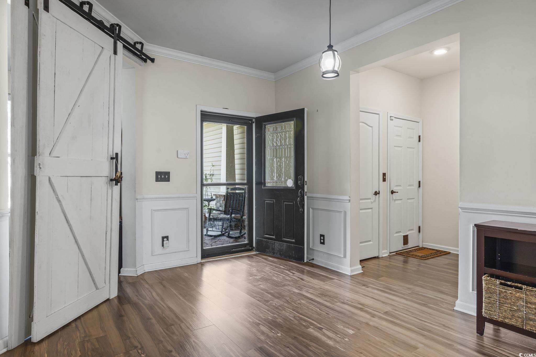 256 Copper Leaf Drive Myrtle Beach, SC 29588 - Photo 5 of 40 Entrance foyer featuring a barn door, crown molding, wood finished floors, and a wainscoted wall