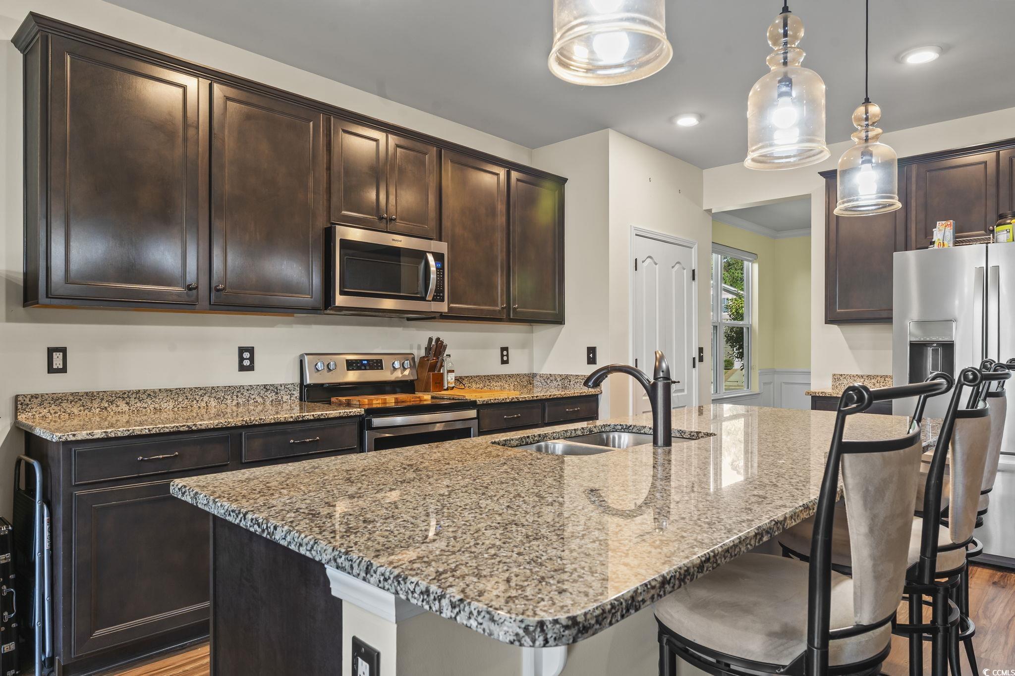 256 Copper Leaf Drive Myrtle Beach, SC 29588 - Photo 7 of 40 Kitchen featuring dark brown cabinetry, appliances with stainless steel finishes, light stone counters, decorative light fixtures, and recessed lighting
