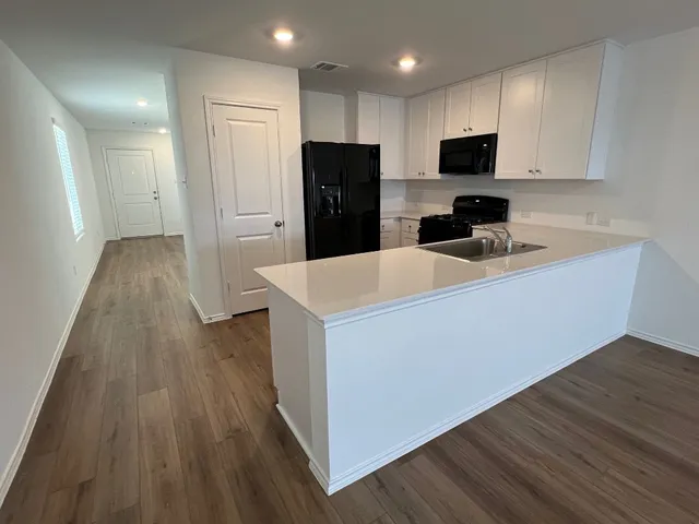 a kitchen with a refrigerator a stove top oven and wooden floor