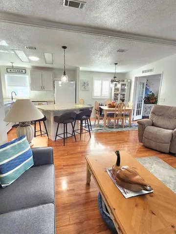 a kitchen with stainless steel appliances granite countertop a sink a stove a refrigerator a dining table and chairs