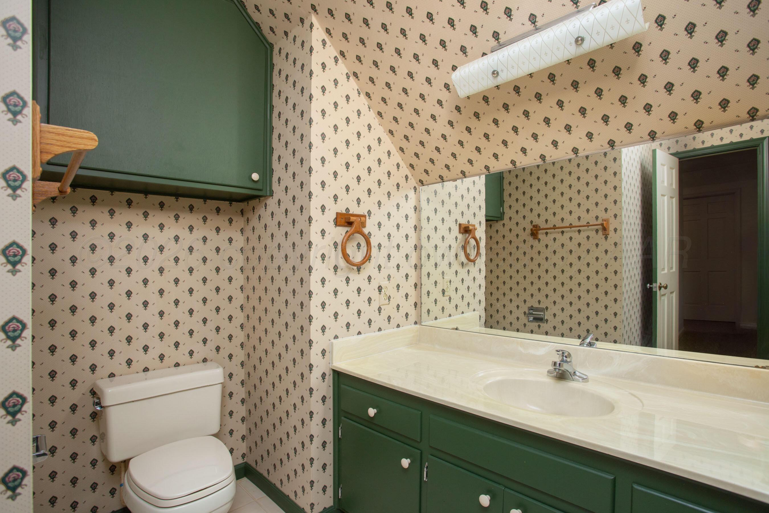 116 Dewey Avenue Amarillo, TX 79124 - Photo 25 of 35 a bathroom with a granite countertop toilet a sink and a mirror