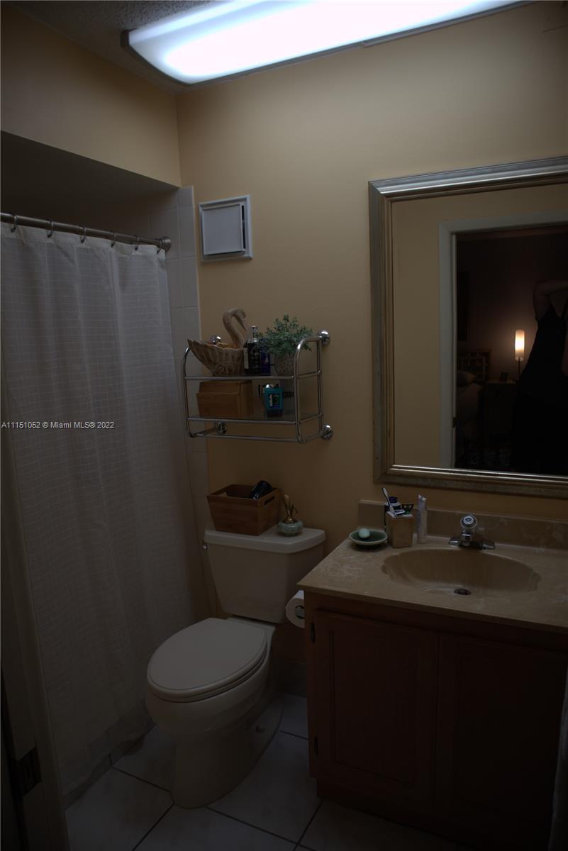 8625 Northwest 8th Street, Unit 420 Miami, FL 33126 - Photo 22 of 26 a bathroom with a toilet a sink and mirror