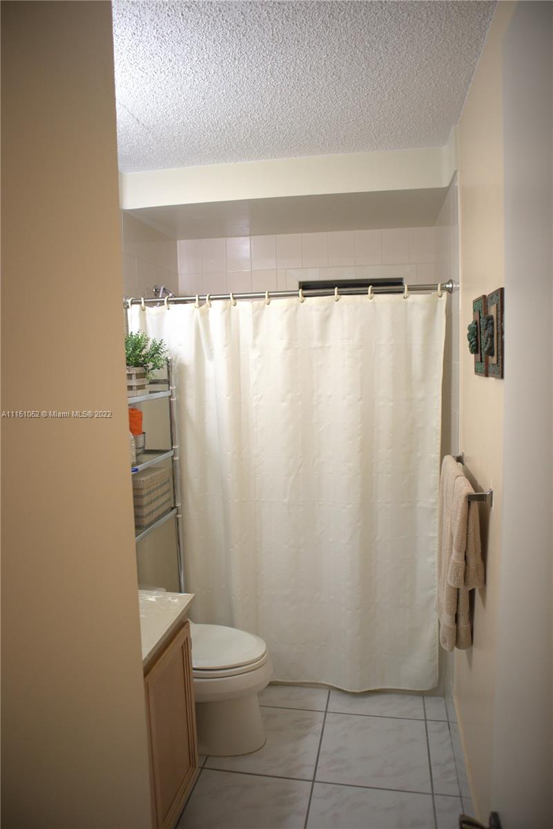 8625 Northwest 8th Street, Unit 420 Miami, FL 33126 - Photo 8 of 26 a bathroom with a toilet and a shower curtain