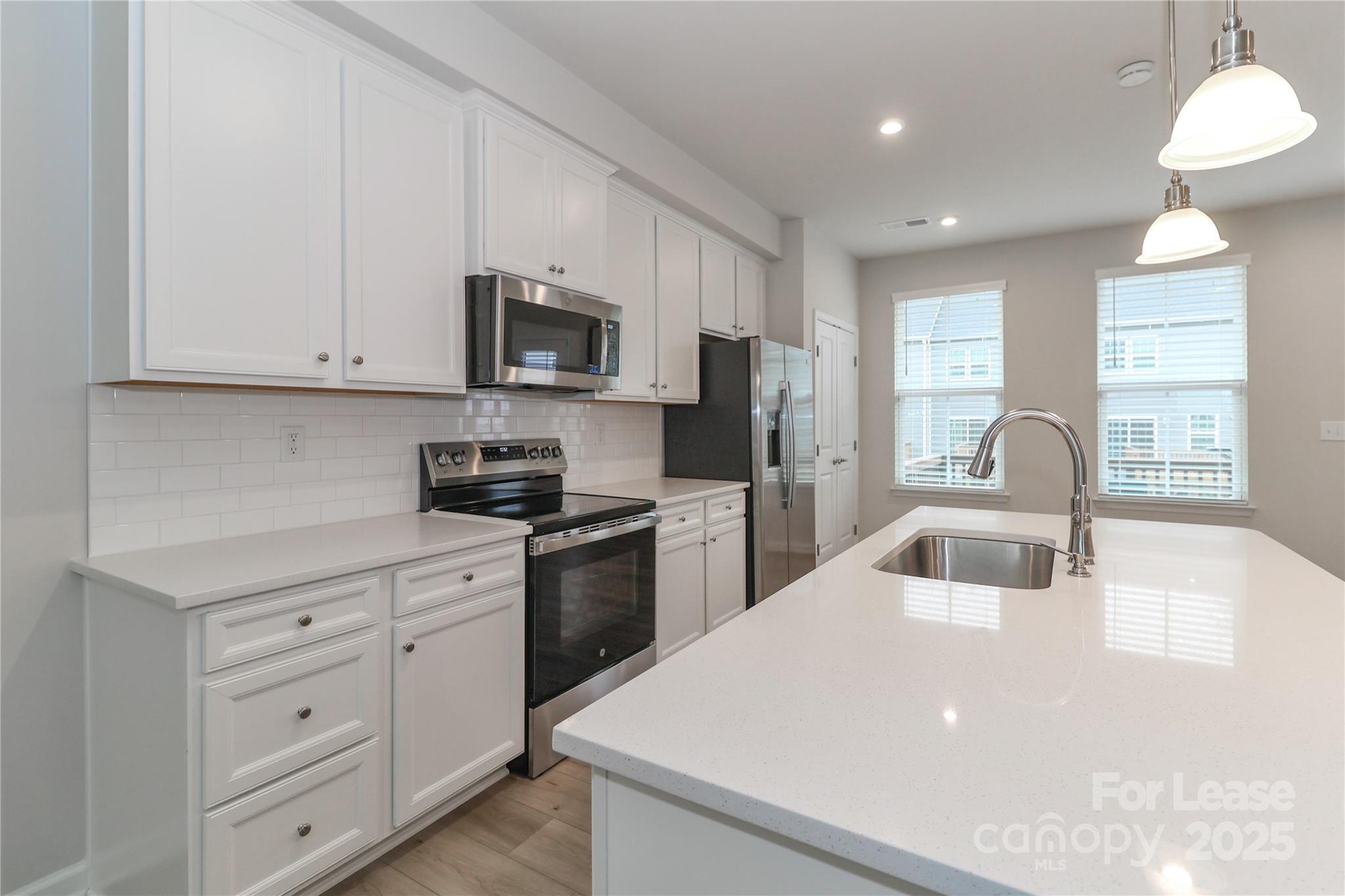 5038 Springarn Court Charlotte, NC 28208 - Photo 13 of 47 a kitchen with white cabinets and stainless steel appliances