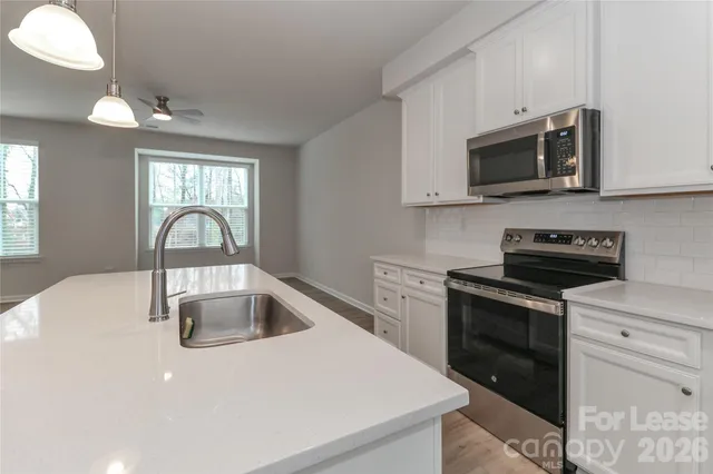 a large kitchen with a center island wooden floor stainless steel appliances and windows