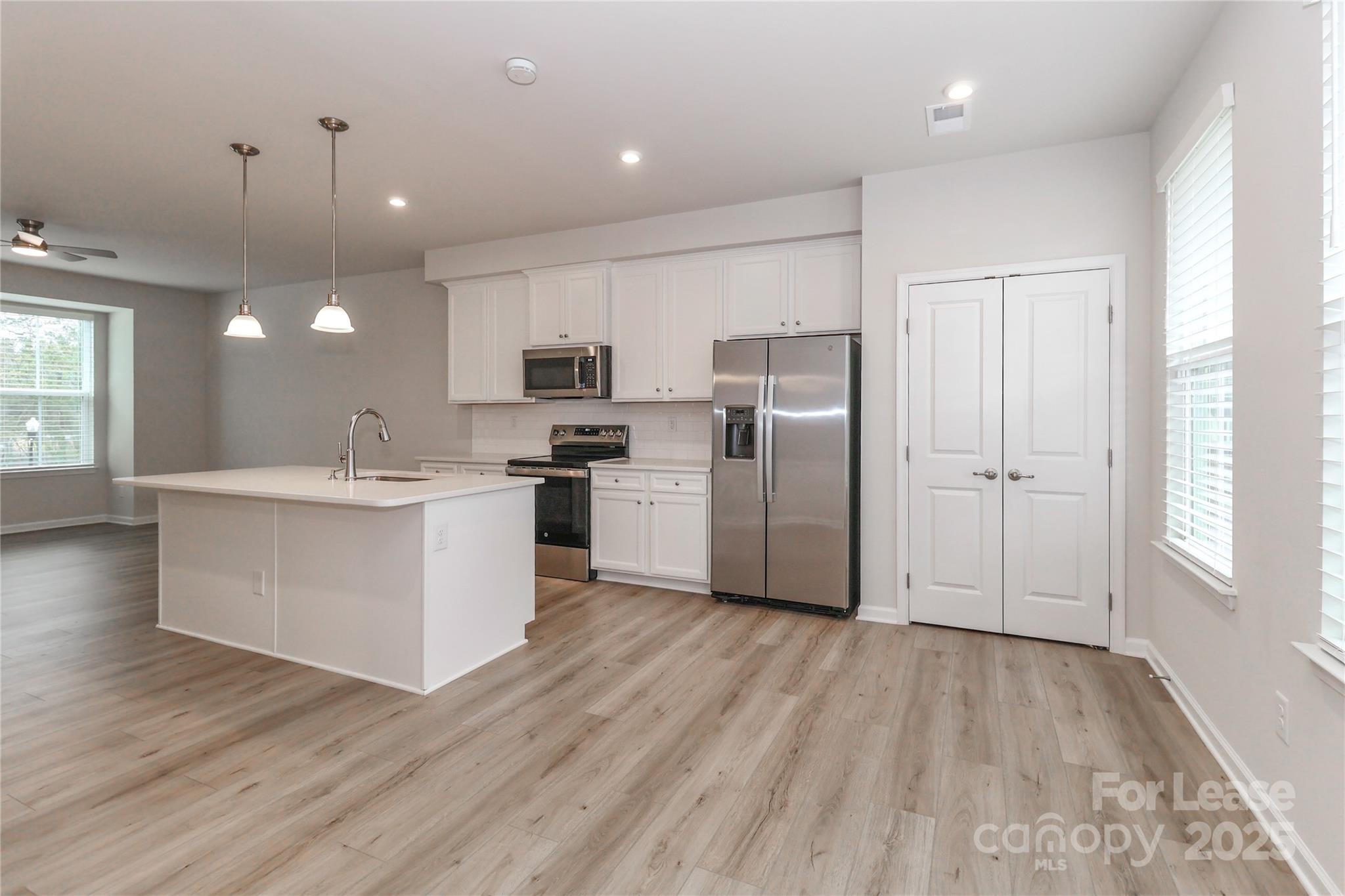 5038 Springarn Court Charlotte, NC 28208 - Photo 10 of 47 a large kitchen with a center island wooden floor stainless steel appliances and windows