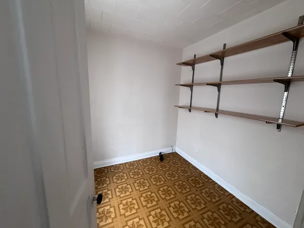 a view of a hallway with wooden floor and a bathroom
