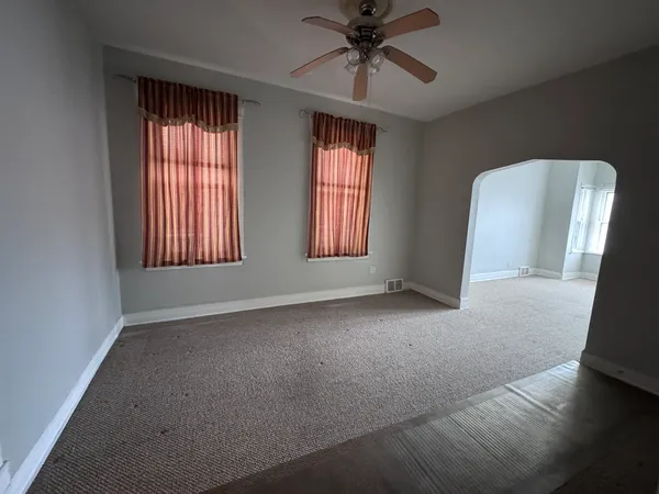 an empty room with windows and fan