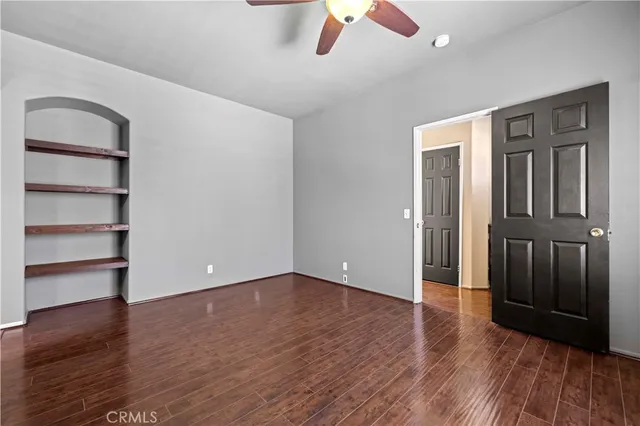 an empty room with wooden floor closet and windows
