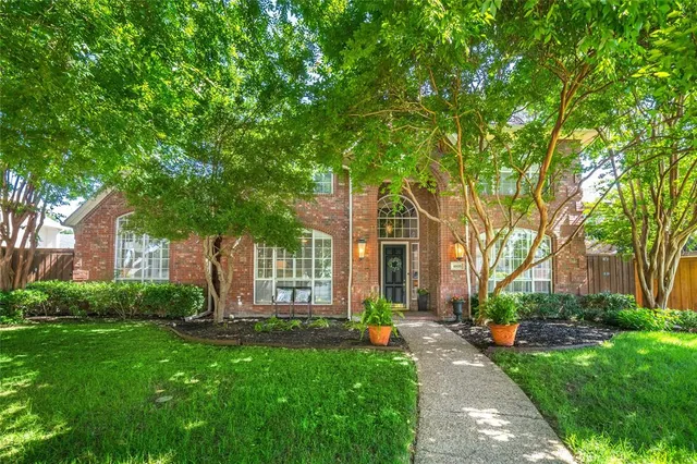 a front view of a house with a garden and trees