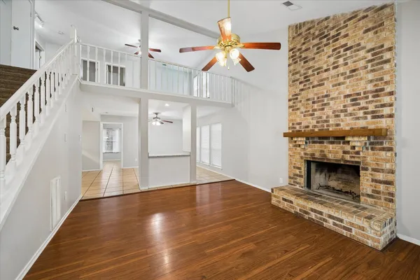 a view of an empty room with wooden floor fireplace and a window