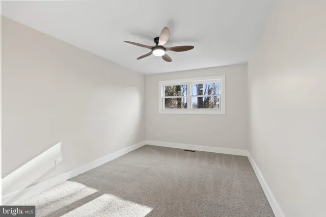 an empty room with a window and a ceiling fan