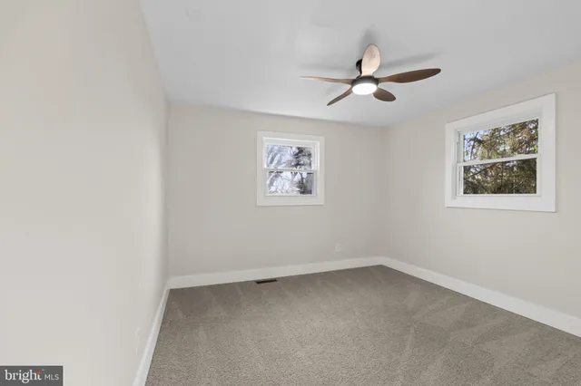 an empty room with a window and a ceiling fan