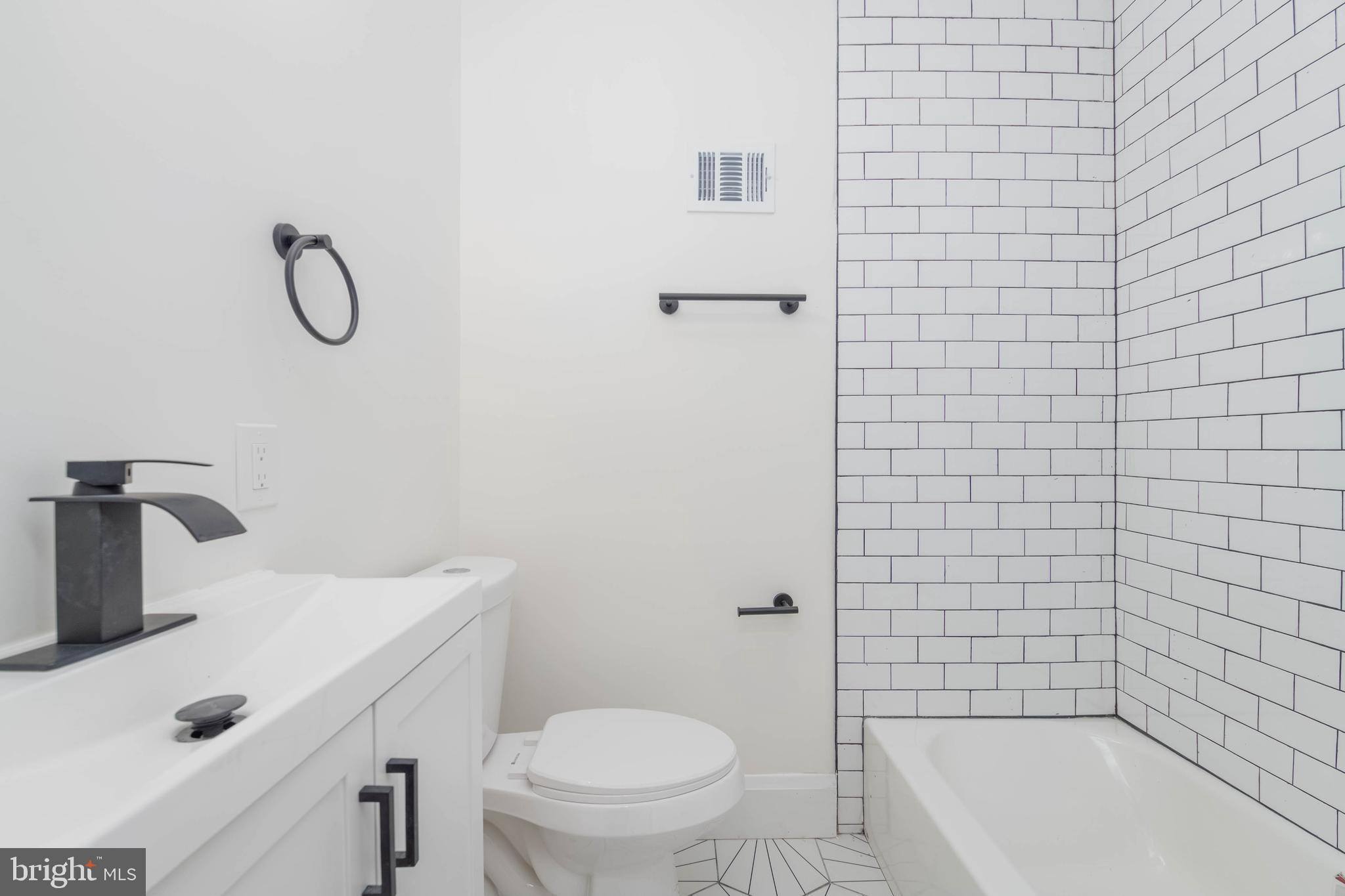 1202 West 42nd Street Baltimore, MD 21211 - Photo 31 of 47 a bathroom with a granite countertop toilet sink and mirror