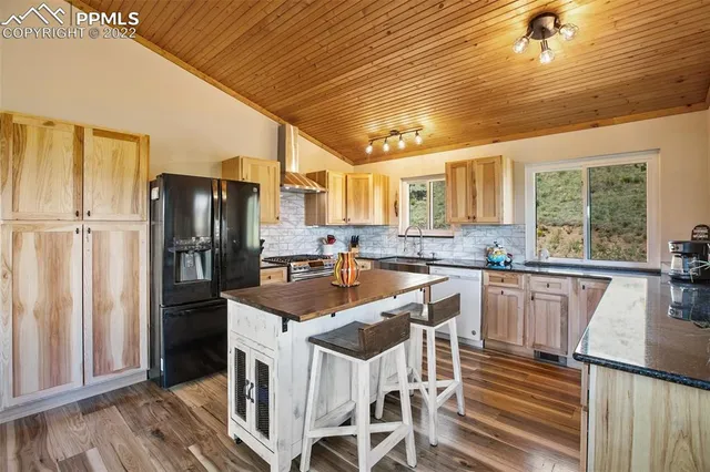 a kitchen with stainless steel appliances granite countertop a refrigerator a sink dishwasher a stove and white countertops with wooden floor