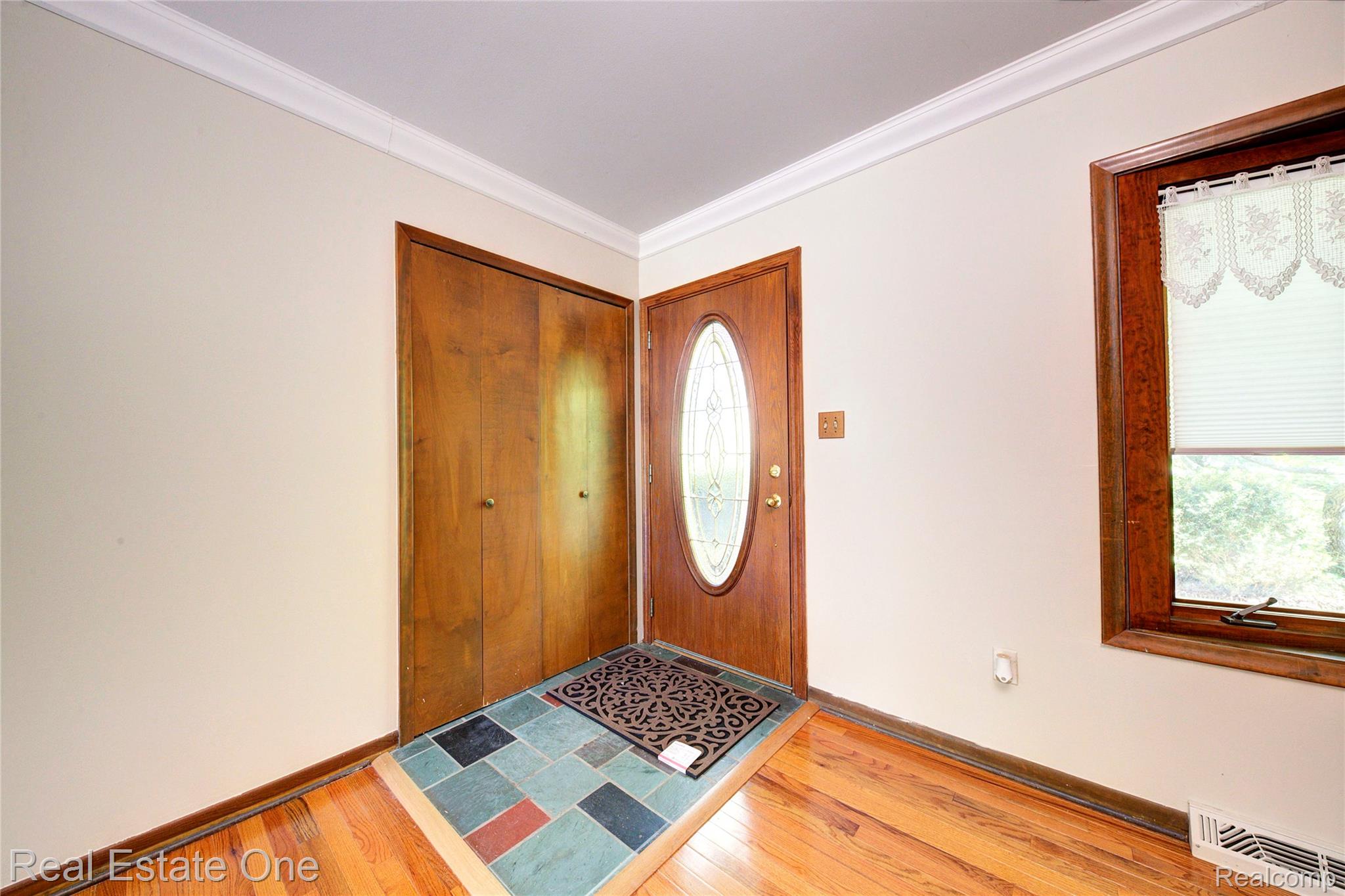 3125 West Commerce Road Milford, MI 48380 - Photo 8 of 63 Entryway featuring a wood-panel door with an oval glass insert, multi-color slate tile flooring, and wood-finish flooring